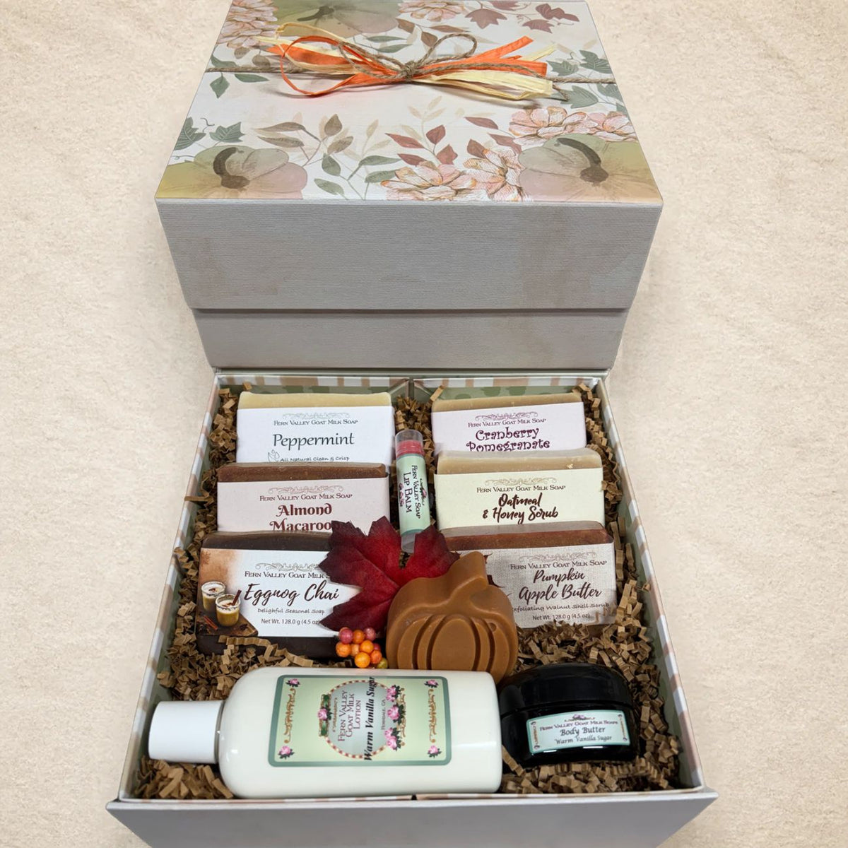 Open autumn gift chest with floral leaf lid filled with six Fern Valley goat milk soaps including Eggnog Chai and Peppermint, Warm Vanilla Sugar lotion, lip balm, and body butter.