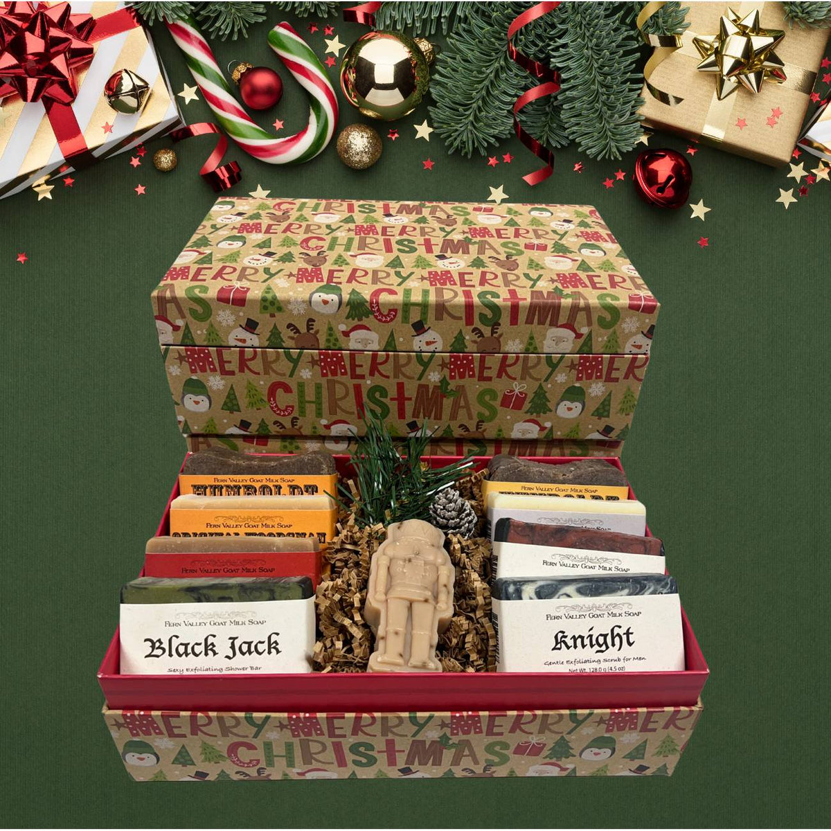 An open festive holiday gift box filled with an assortment of handcrafted masculine goat milk soaps, a nutcracker-shaped novelty soap, and decorative pine cone accents, styled with Christmas presents.