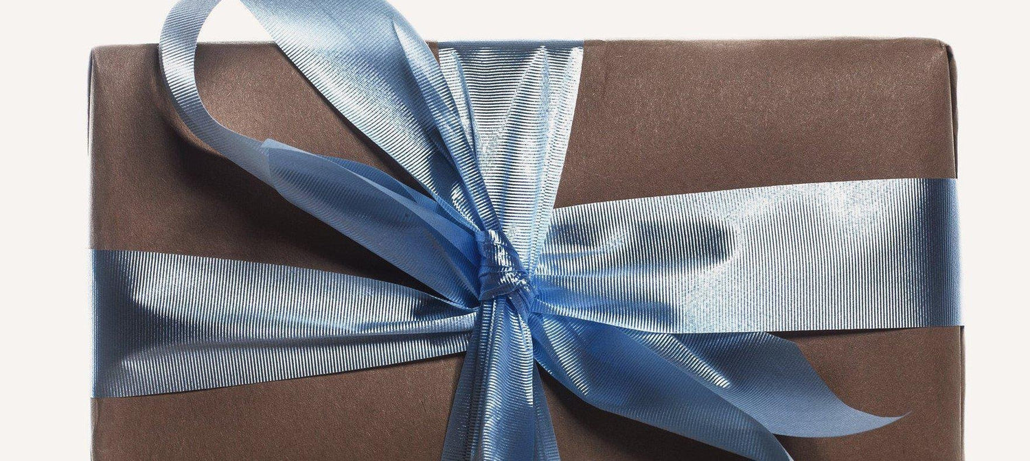 Gift box wrapped in brown Kraft paper with dusty blue ribbon.