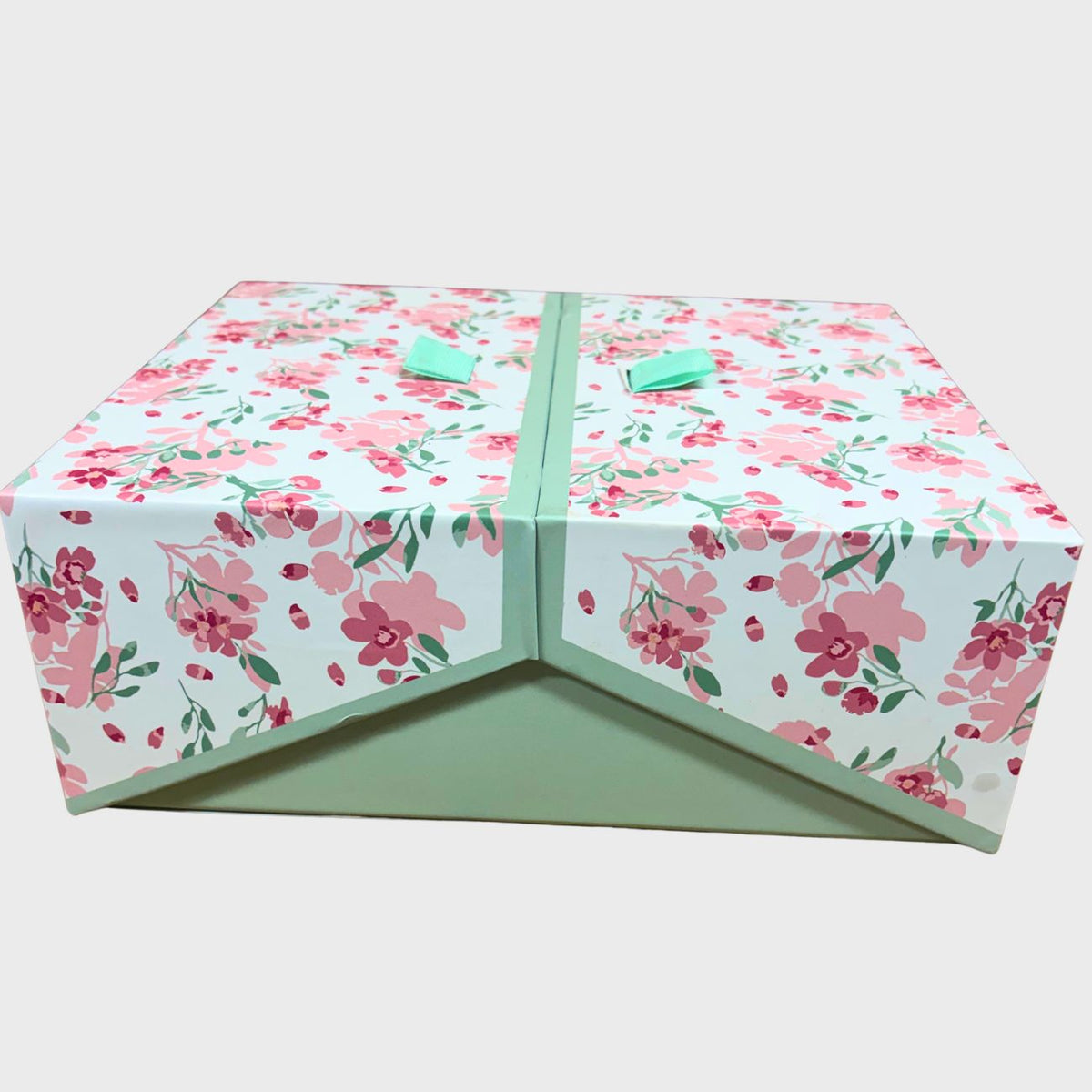 A rectangular gift box with a white background covered in a pink and green floral pattern, featuring a mint green center panel and matching mint green handles on top.