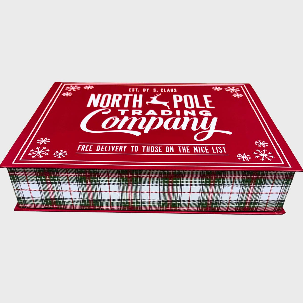 A Christmas-themed gift box from North Pole Trading Company, featuring a red lid with white text and snowflake designs, and a green, red, and white plaid patterned side, shown on a light gray background.