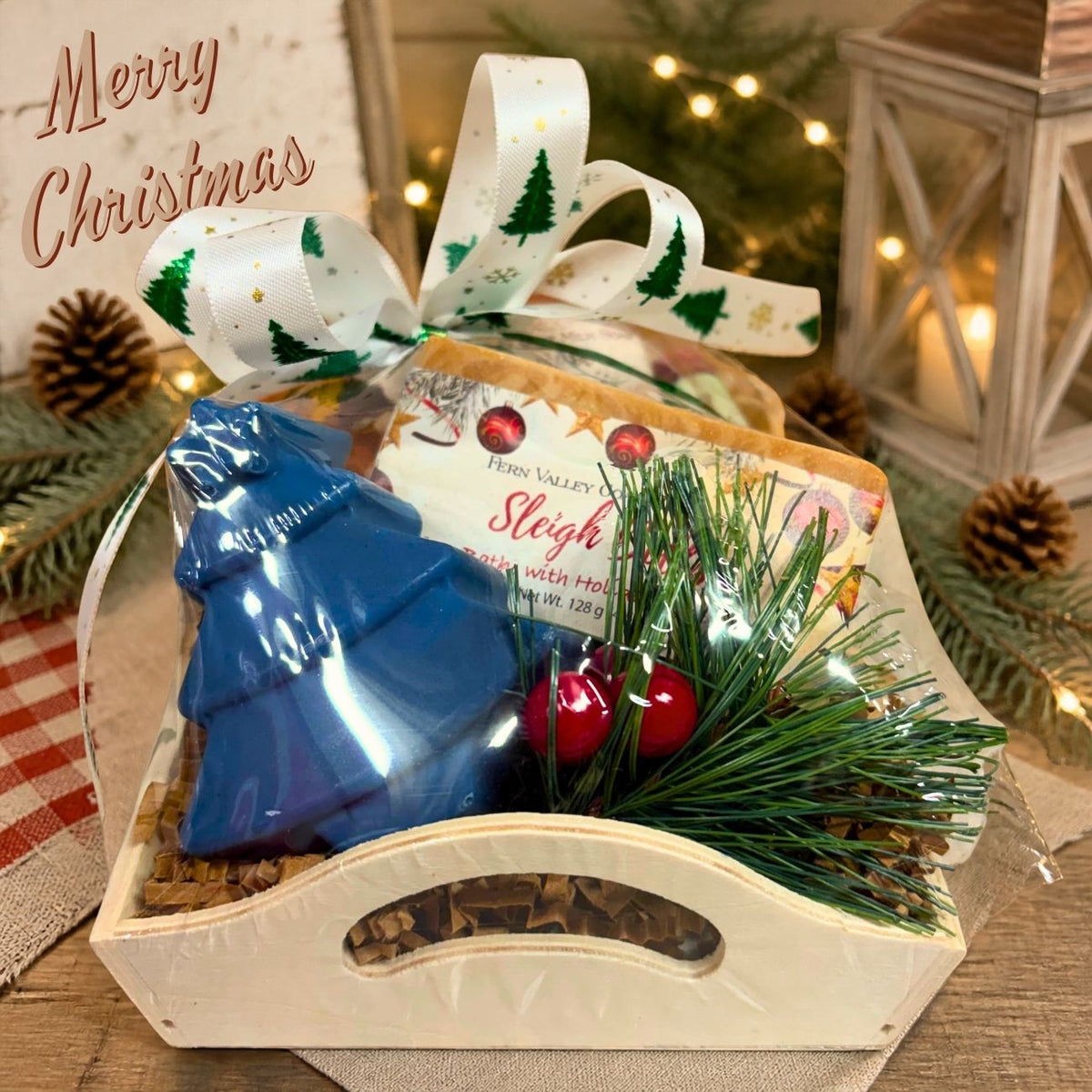 Handmade holiday goat milk soap gift crate featuring a blue pine tree shaped soap and a Sleigh Bells holiday bar soap.